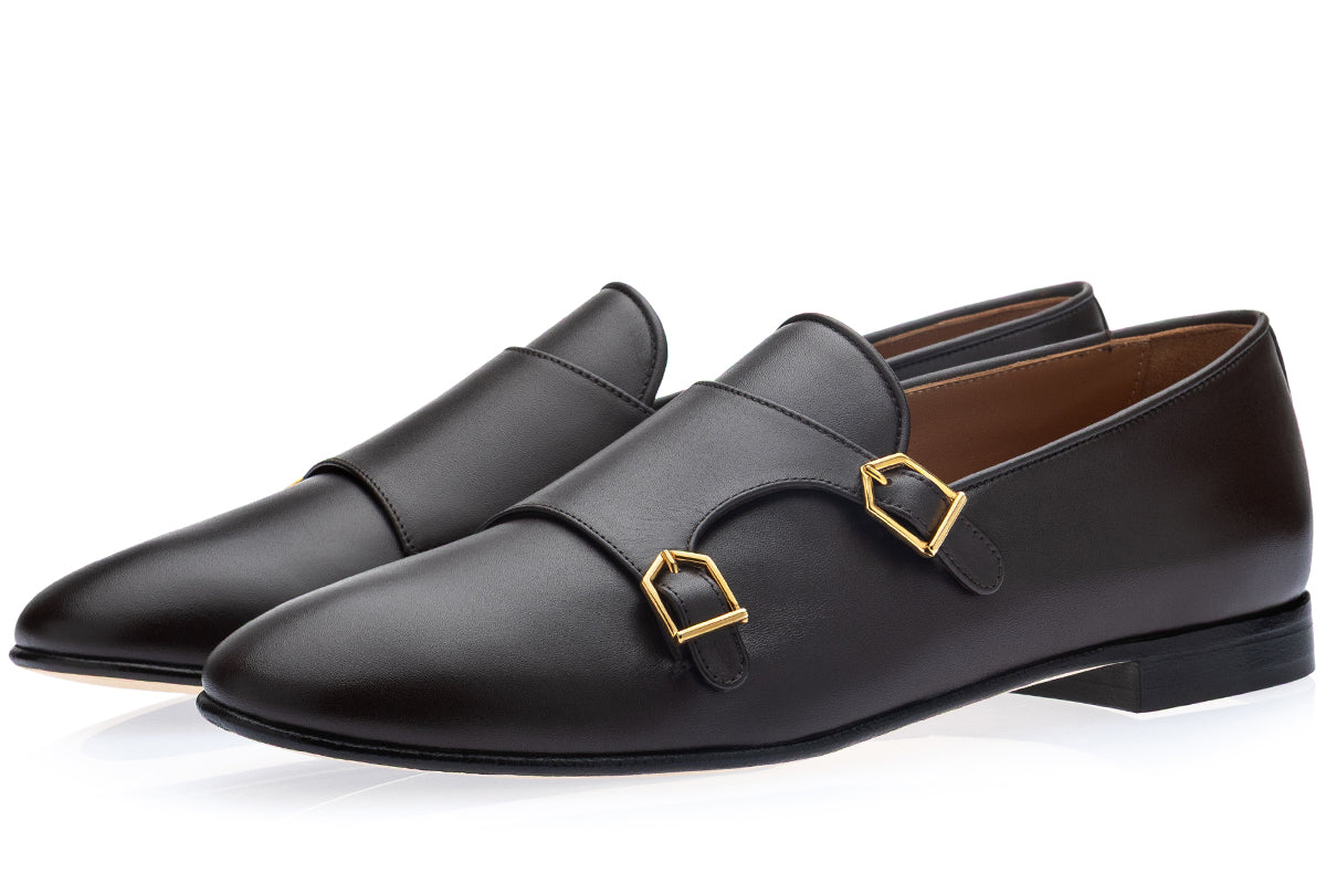 A pair of men's cocoa leather slip-on loafers with double buckle straps and gold-tone hardware, displayed on a clean white background.