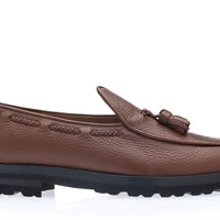 A single brown pebbled leather loafer with a decorative tassel on the vamp and a thick black lug sole, shown from a side profile on a white background. | Image 3