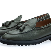 A pair of dark musk green pebbled leather loafers with decorative tassels on the vamp and thick black lug soles, shown on a clean white background. | Image 1