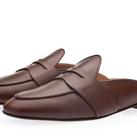 A pair of dark brown cognac leather mule loafers with a wide decorative strap across the vamp, shown on a clean white background. | Image 1