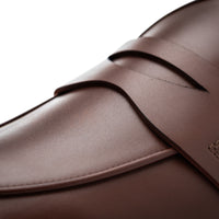 Close-up of a dark brown leather loafer showing the smooth texture, precise stitching, and the side strap detail against a clean white background. | Image 5